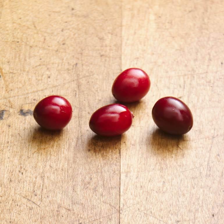Quatre canneberges posées sur une surface en bois.