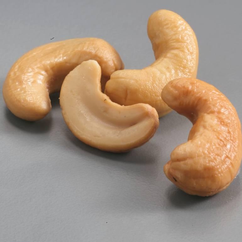 Four cashew nuts on a flat surface.